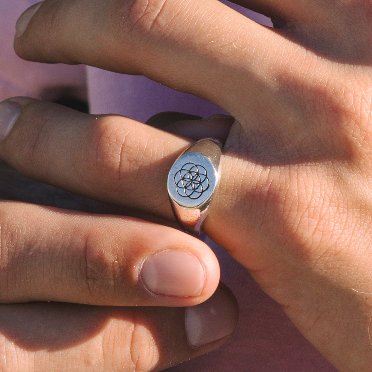 A detailed close-up of the Billie Jo UNITY RING, showing the intricate geometric flower of life pattern on the sterling silver signet ring, worn on a finger.