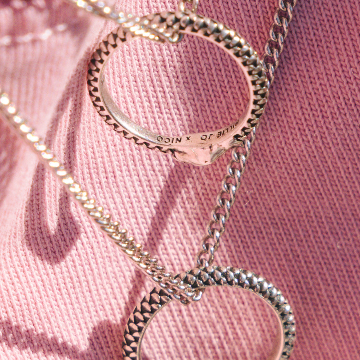 Close-up of two Billie Jo Ouroboros Pendants, showing the detailed snake scale texture and the engraved brand logo on the sterling silver surface.