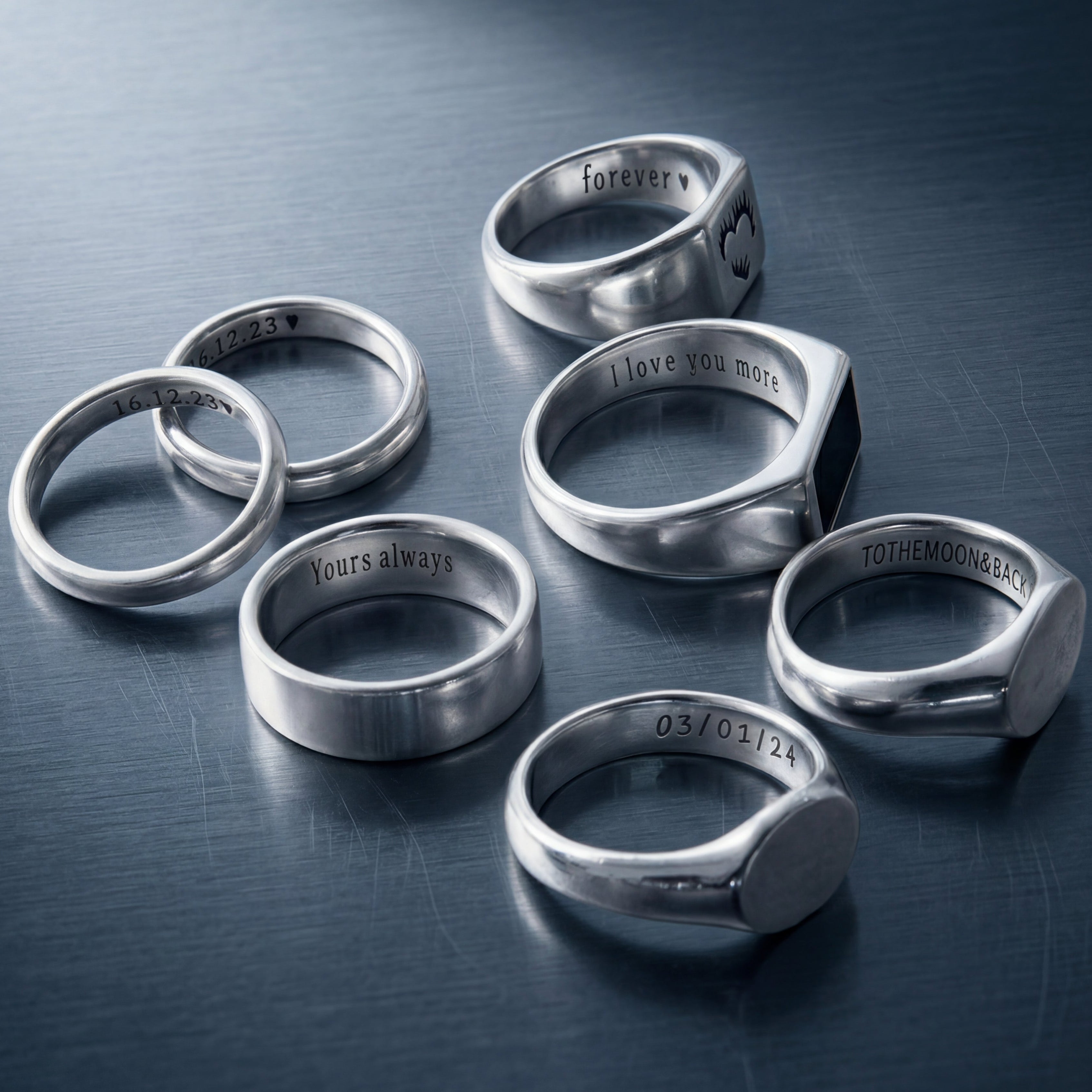 Set of silver rings with engraved text on a dark surface