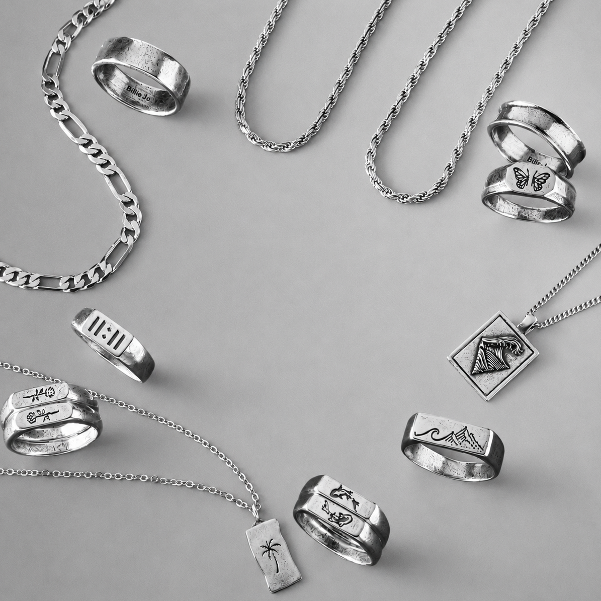 Collection of silver rings and necklaces on a gray background