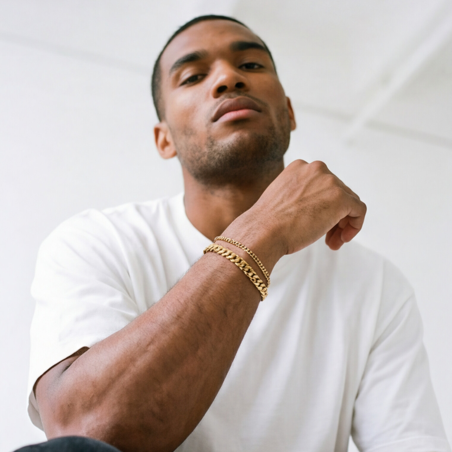 A man wearing a gold stainless steel bracelet layered - from Australian jewellery brand Billie Jo, styled for everyday casual wear.