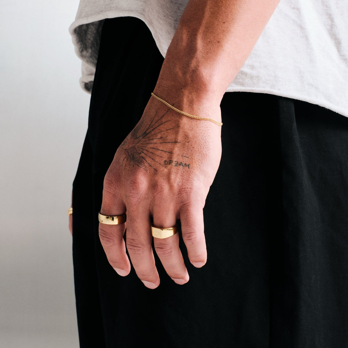 Men's Gold Canvas Ring in 18k gold infused stainless steel, worn on his left index finger, hand hanging by his side