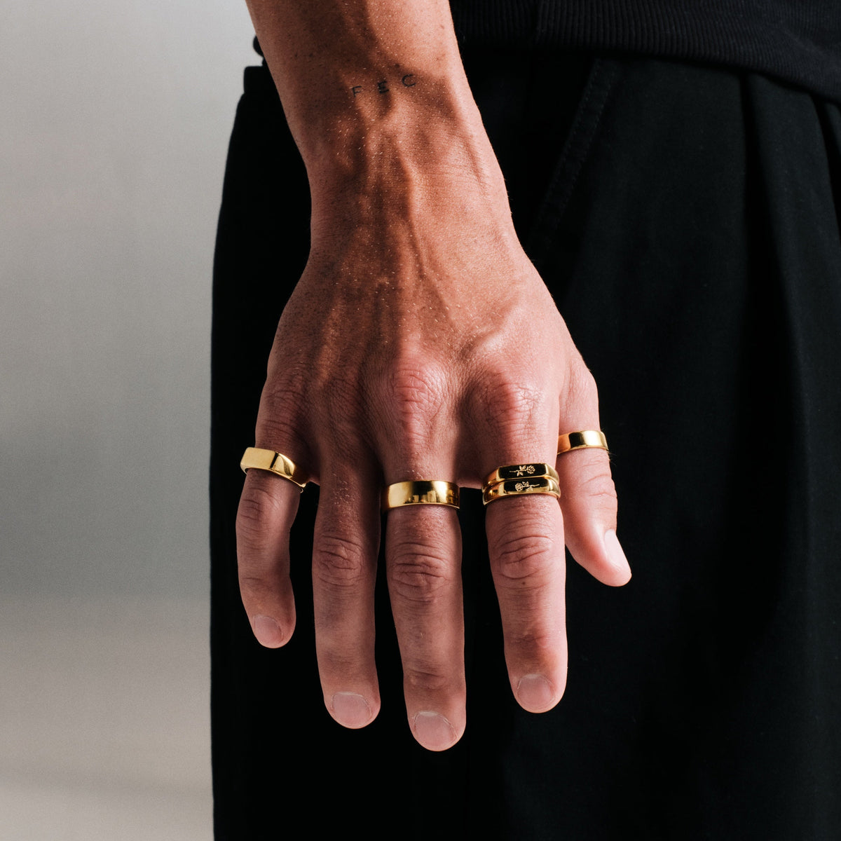Men's Gold Canvas Ring in 18k gold infused stainless steel, worn on his right middle finger, black tee, black pants