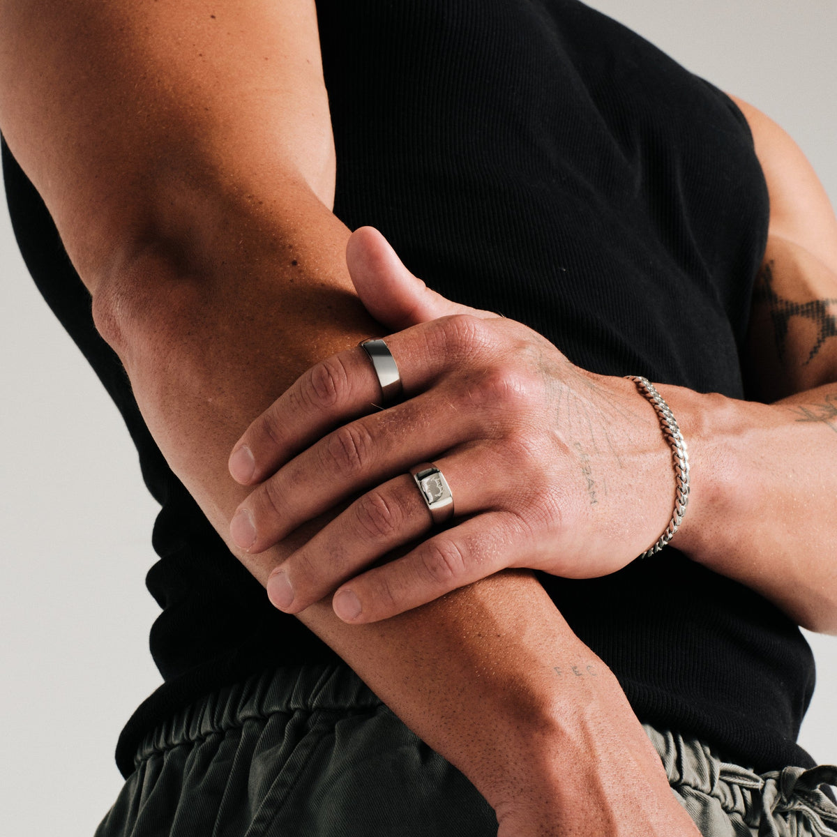 Men's Canvas Ring in 316L stainless steel, silver finish, worn on his left index finger, hand gripping his other forearm