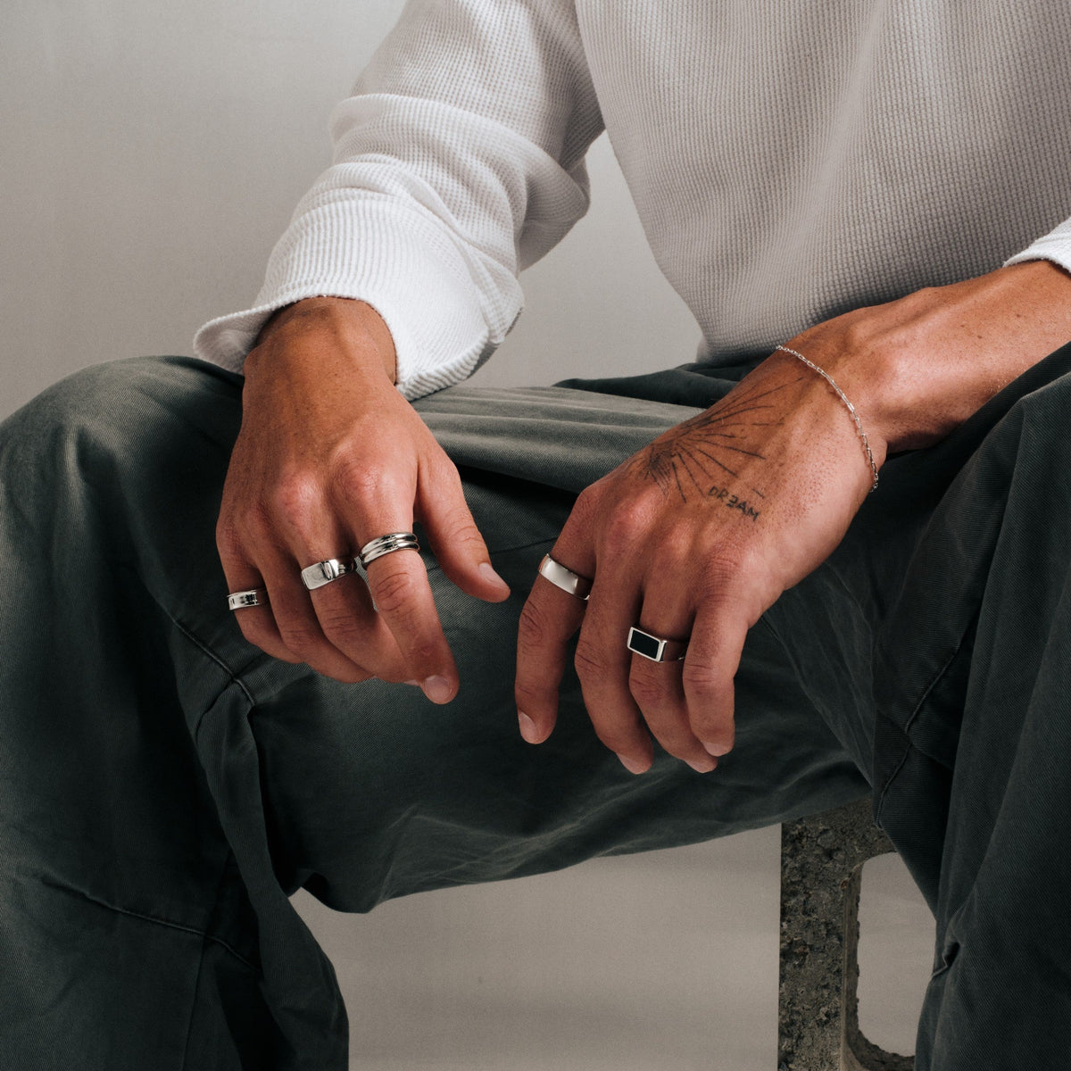 Men's Canvas Ring in 316L stainless steel, silver finish, worn on the index finger, seated, both hands over his knee