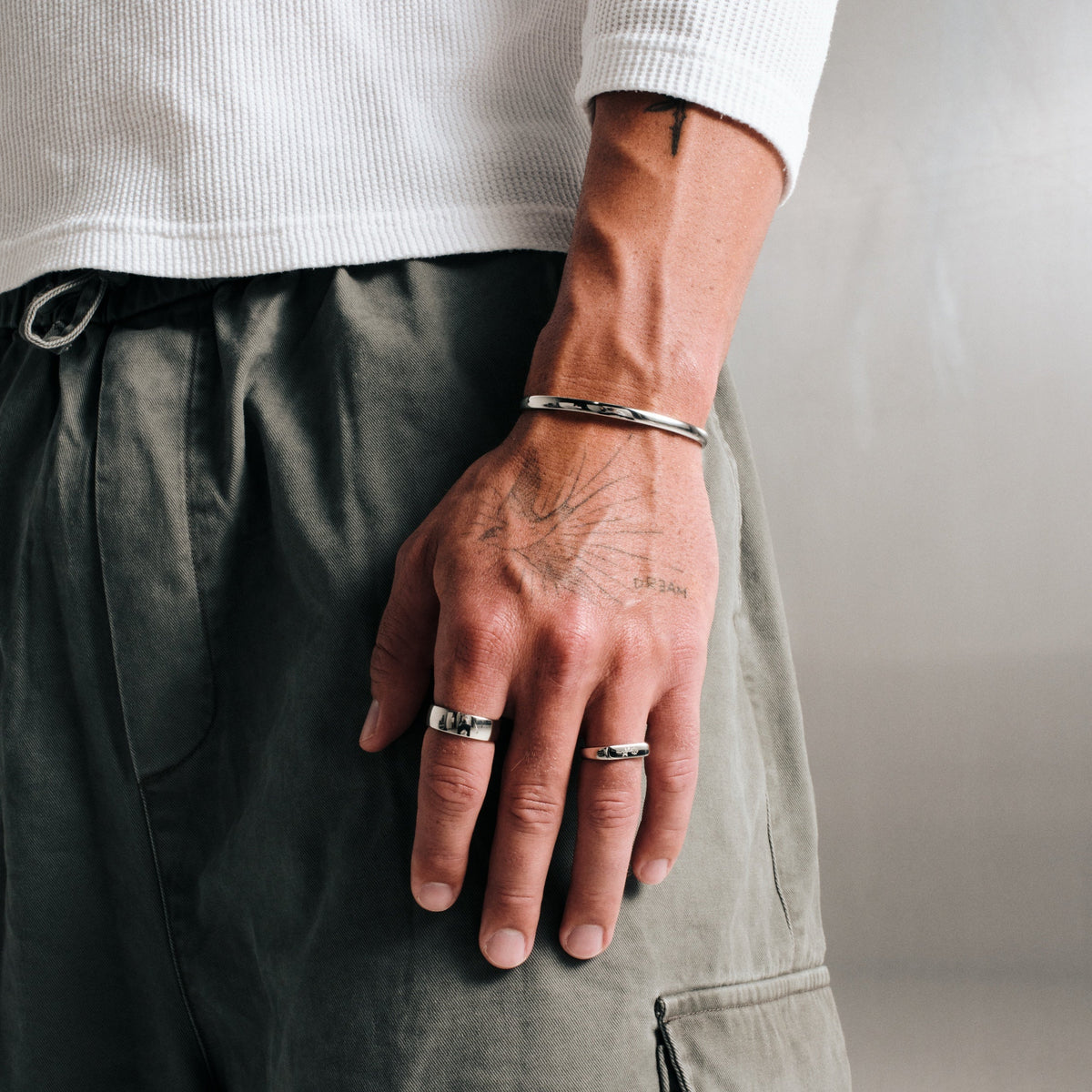 Men's Drifter Cuff in 316L stainless steel, silver finish, worn on his left wrist, hand by his side