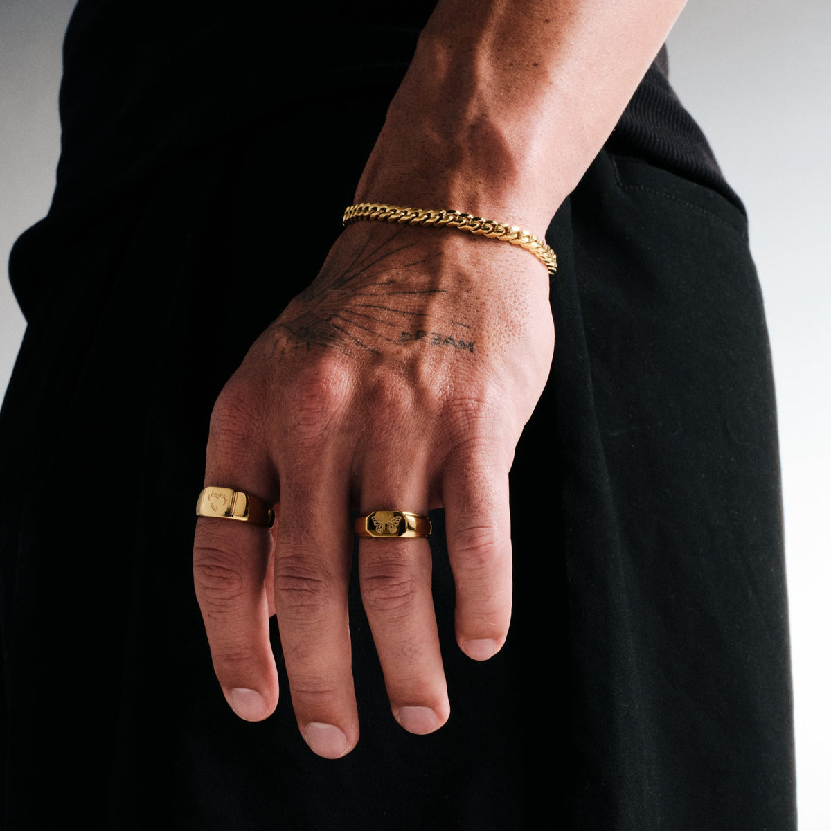 Men's Gold Ember Ring in 18k gold infused stainless steel, worn on his left index finger, hand hanging by his side