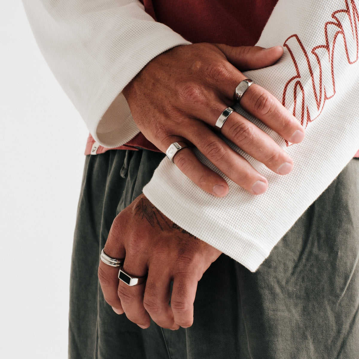 Men's Ember Ring in 316L stainless steel, silver finish, worn on the index finger, hand resting on his forearm