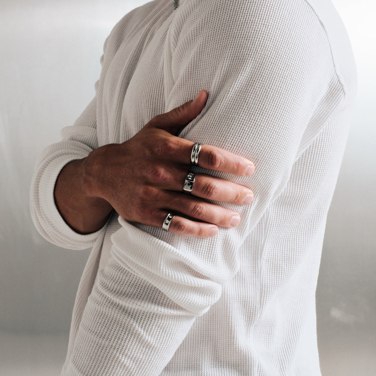 Men's Forge Ring in 316L stainless steel, silver finish, worn on the index finger, hand gripping his upper arm