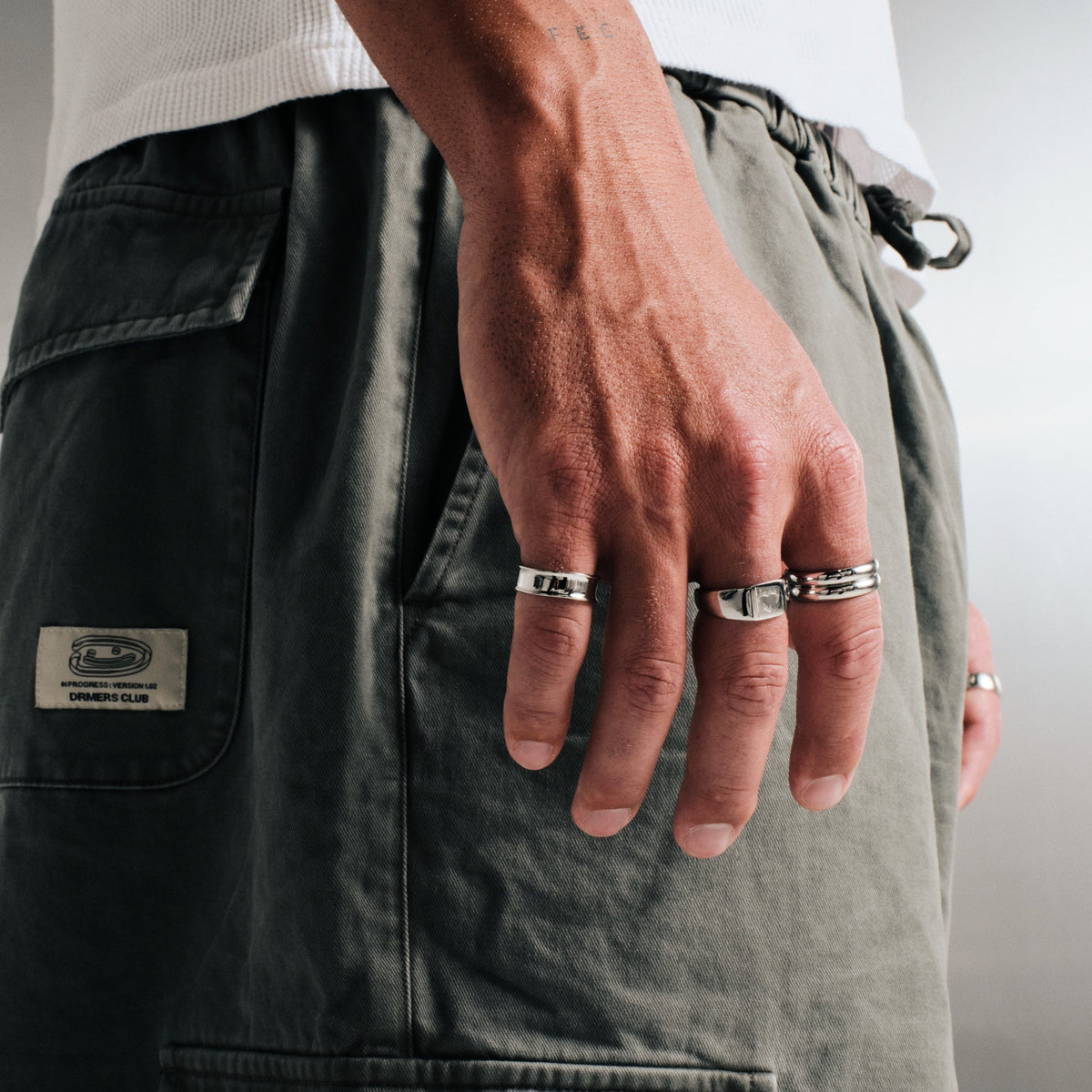 Men's Forge Ring in 316L stainless steel, silver finish, in a stack, hand by his side, white waffle top, olive cargo pants