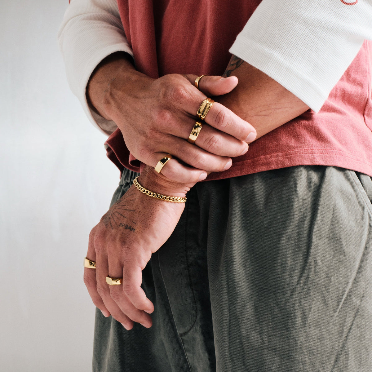 Men's Gold Genesis Ring in 18k gold infused stainless steel, in a stack, right hand over left forearm