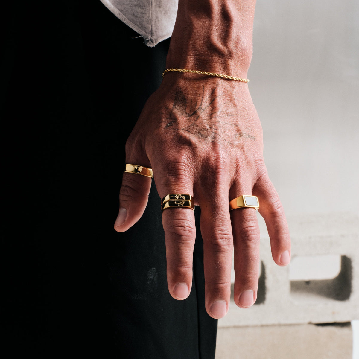 Men's Gold Koi Stackers in 18k gold infused stainless steel, both worn on his left index finger, black pants