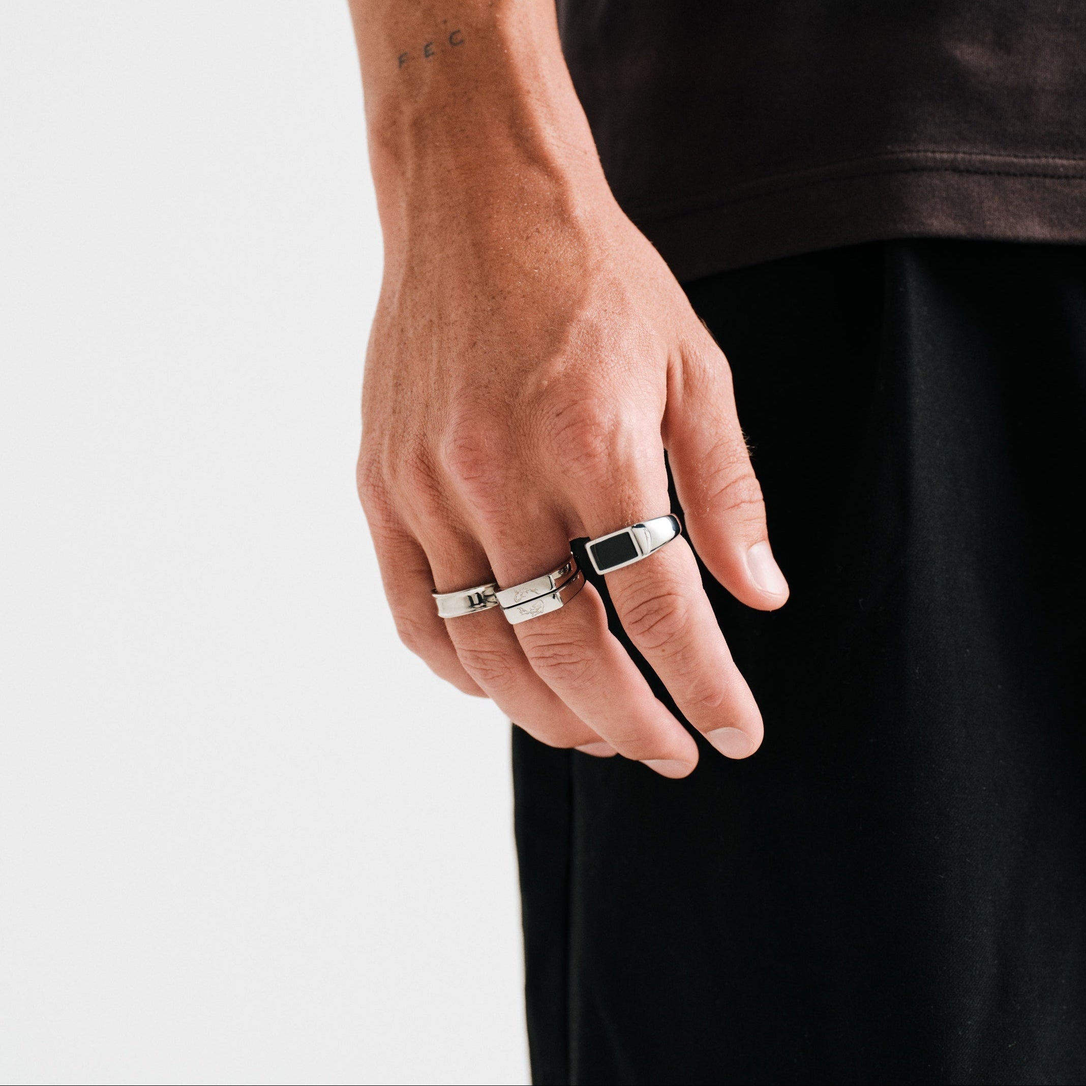 Men's Koi Stackers in 316L stainless steel, silver finish, both worn on his right middle finger, hand relaxed at his side