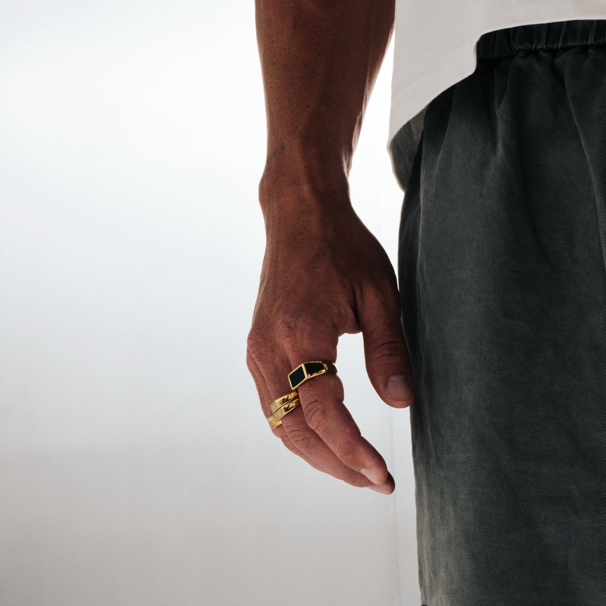 Men's Gold Onyx Ring in 18k gold infused stainless steel, worn on his right index finger, hand by his side