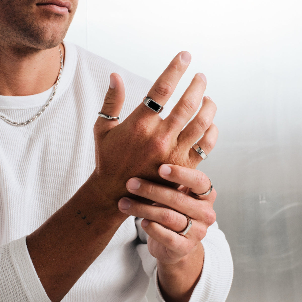 Men's Onyx Ring in 316L stainless steel, silver finish, worn on his right index finger, with a steel chain necklace