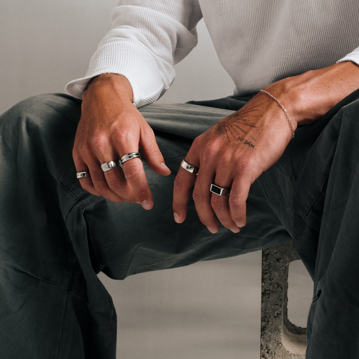 Men's Onyx Ring in 316L stainless steel, silver finish, in a stack, seated, hands resting over his knee