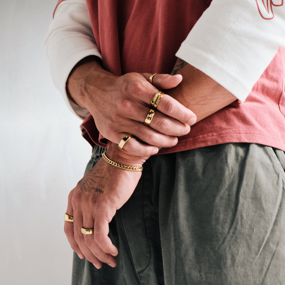 Men's Gold Rosa Stackers in 18k gold infused stainless steel, worn on the index finger, arms folded
