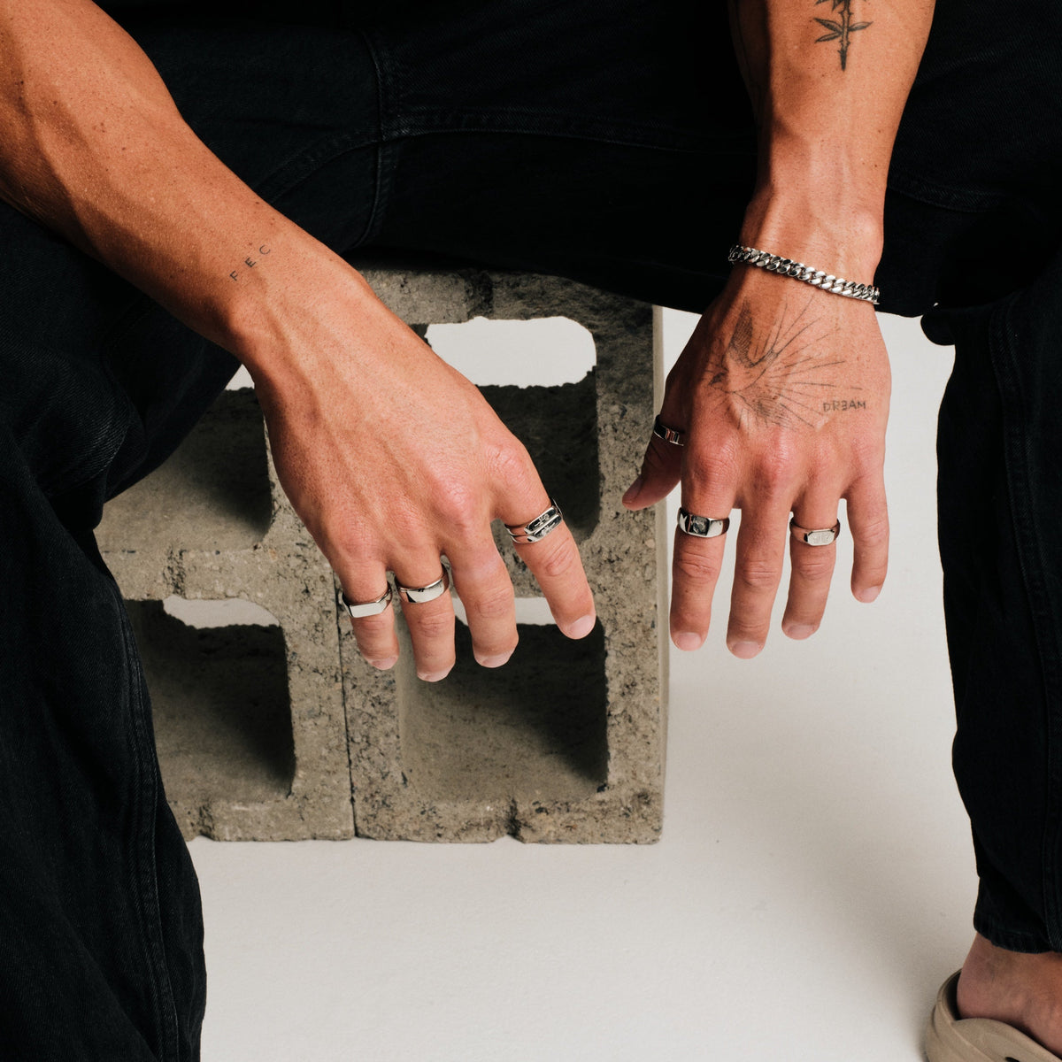 Men's Rosa Stackers in 316L stainless steel, silver finish, worn on the index finger, black jeans