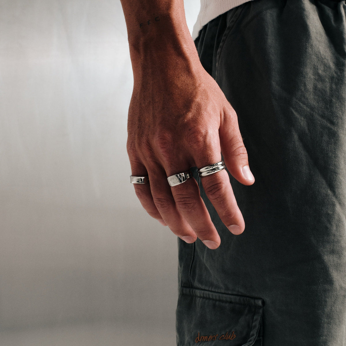 Men's Stacker Rings in 316L stainless steel, silver finish, both worn on his right index finger, hand relaxed at his side