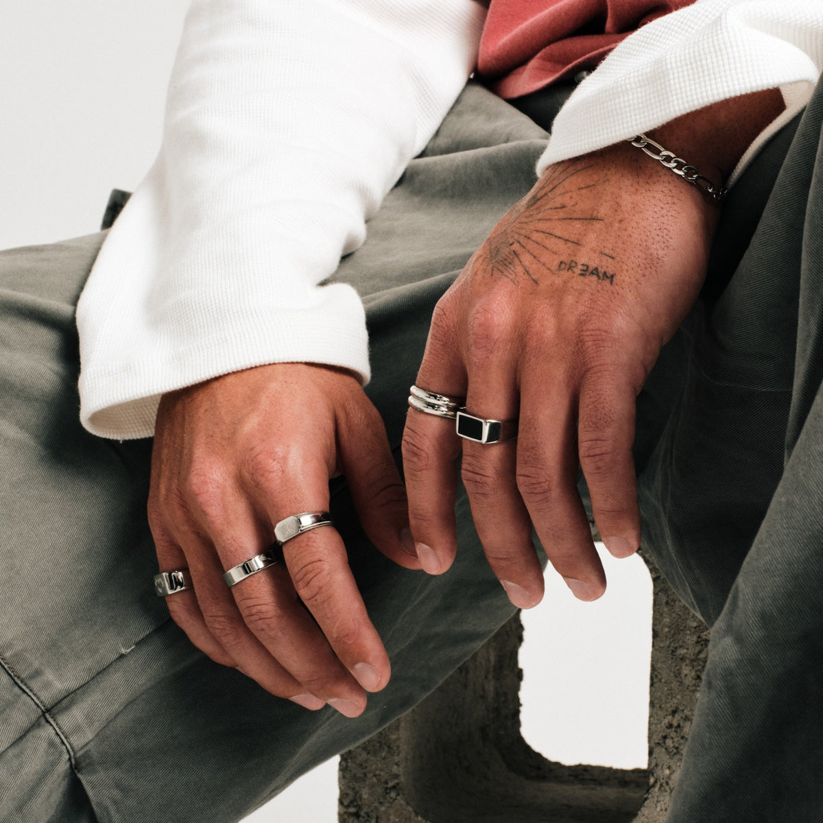 Men's Stacker Rings in 316L stainless steel, silver finish, both worn on his left index finger, with a Figaro chain bracelet