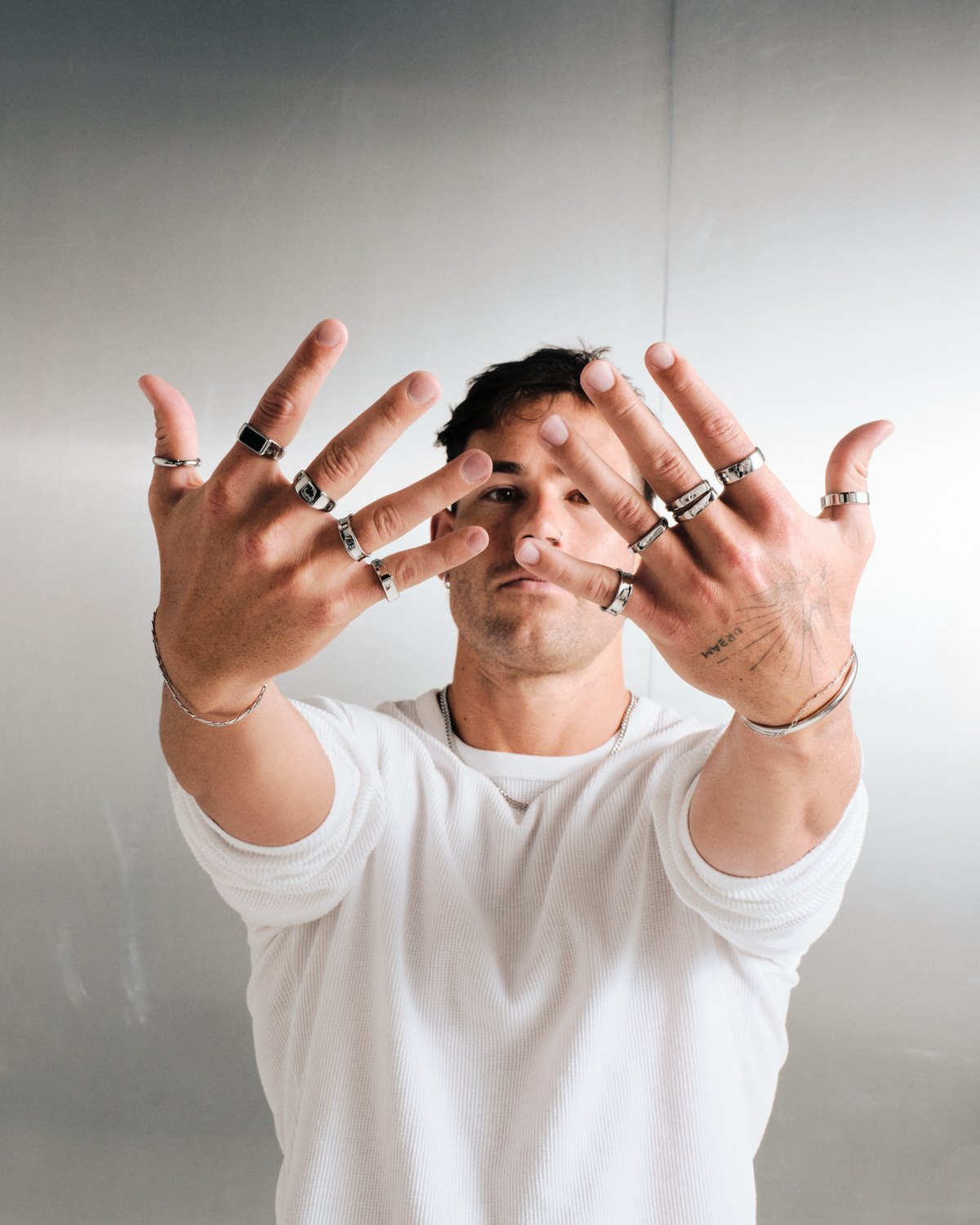 Man holding both hands to camera with stacked silver stainless rings