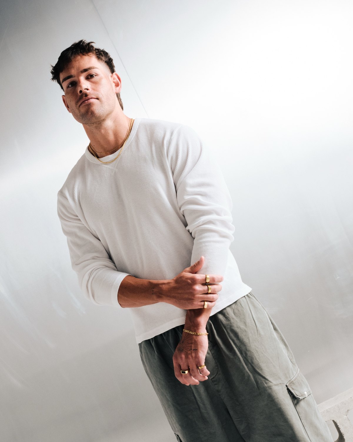 Man in a white long sleeve wearing gold stainless rings and a bracelet