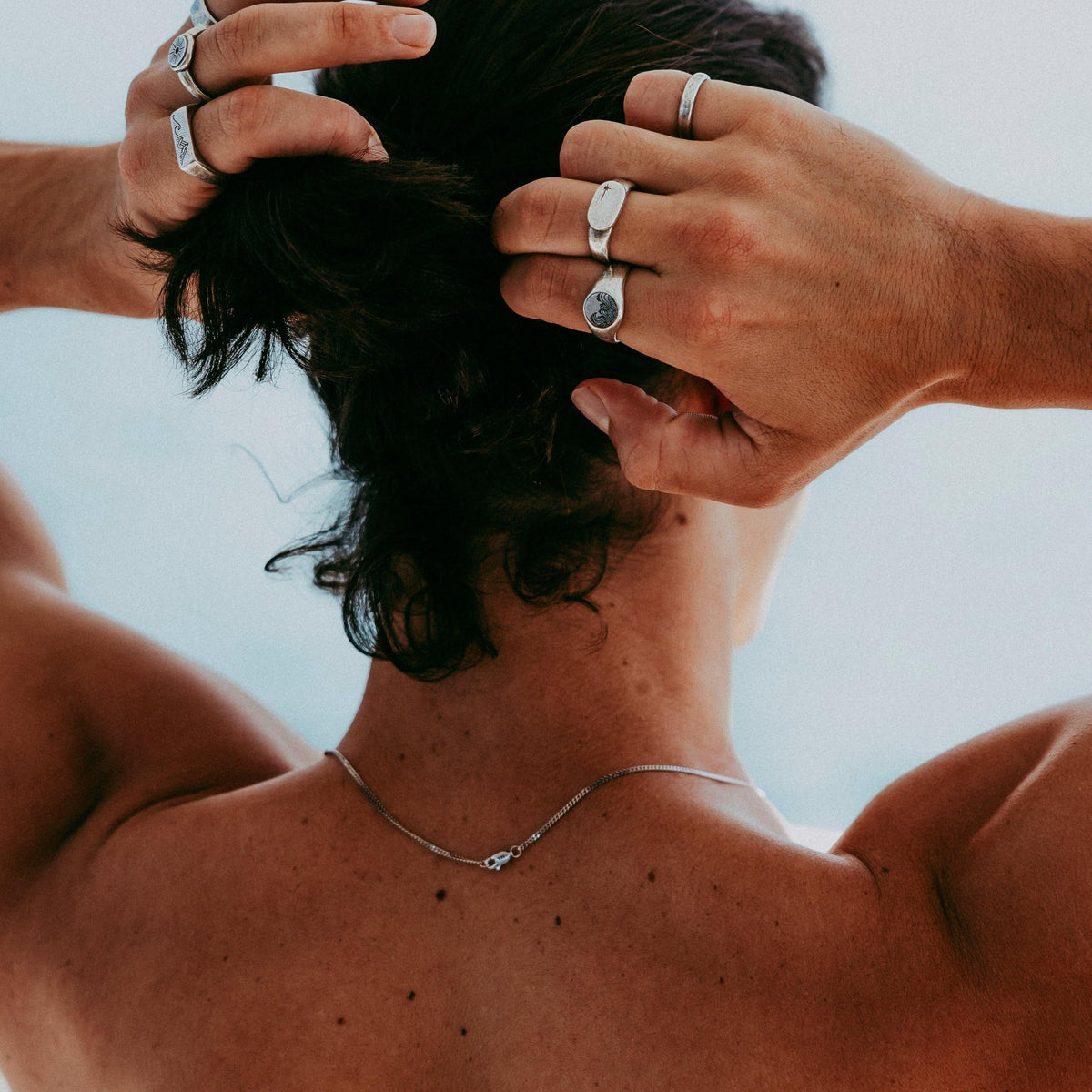 A man wearing the sterling silver Current Ring and other Billie Jo jewellery runs his hands through his dark hair, showing a modern, masculine style.