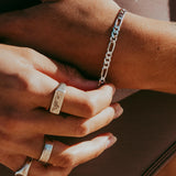 A close-up on-hand shot of the men's Figaro Bracelet in sterling silver by Billie Jo. The model is also wearing several silver rings, showcasing a layered and stylish men's jewellery look.